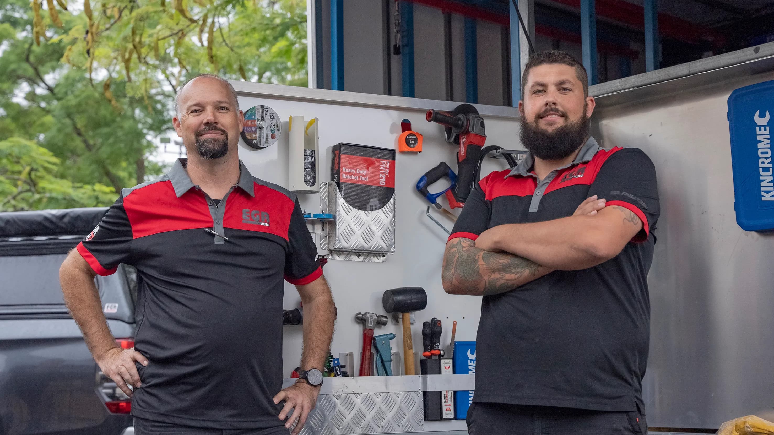 Two EGR technicians in branded uniforms standing in a fitment workshop