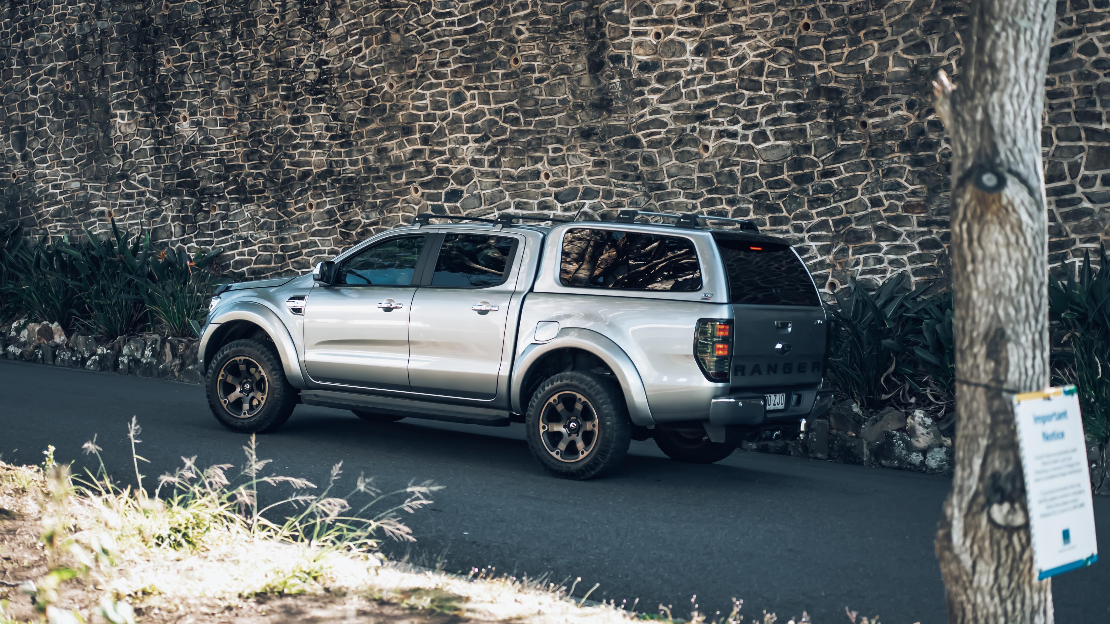 a silver 4 door ute with an EGR Canopy fitted in front of a rock wall