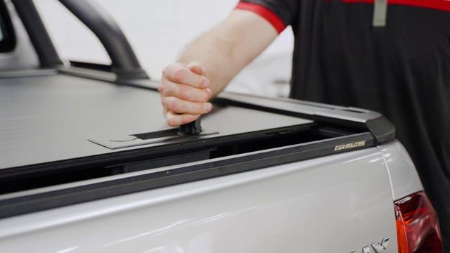 man opening a Manual EGR Rolltrac on a ute with the manual latch