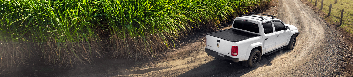 ute driving on a dirt road around a field
