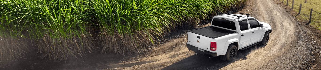 ute driving on a dirt road around a field