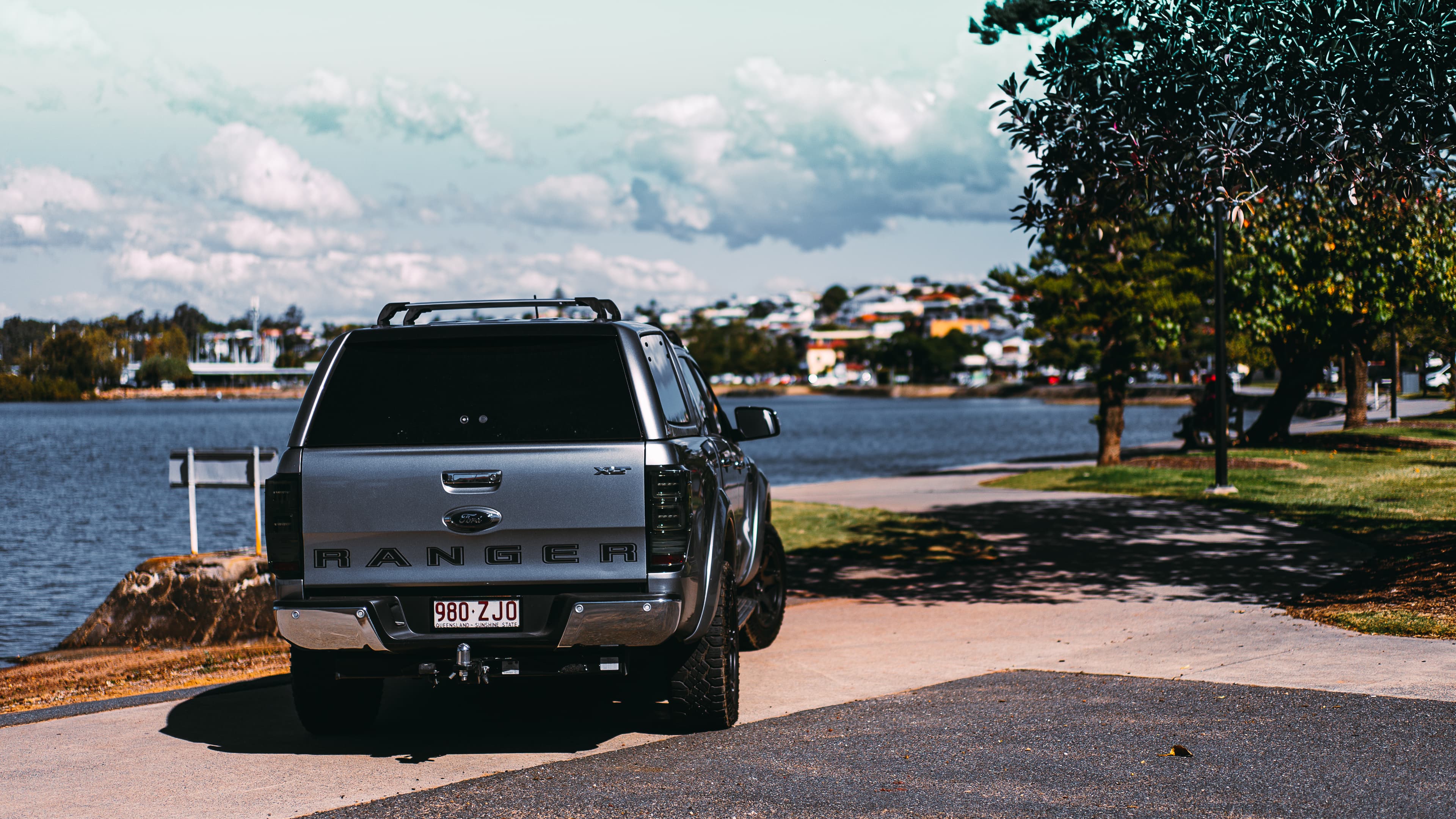 a gray ute fitted with an EGR canopy parked in front of a bay of water